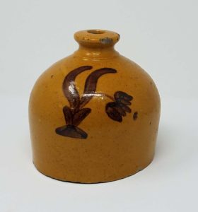 Whitewater earthenware countertop string holder with lead glaze on the exterior and unglazed interior. Manganese flower decoration. It has no bottom so it can sit on a countertop over a ball of string. We attribute this piece to the Depot Pottery. Private collection.