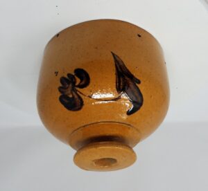 Hanging String Holder with lead glaze and manganese flower decoration. There are three original holes near the base to allow hanging it and a hole at the top for the string. Shopkeepers used these for wrapping packages. Attributed to the Whiton Street Potter.  Private collection.