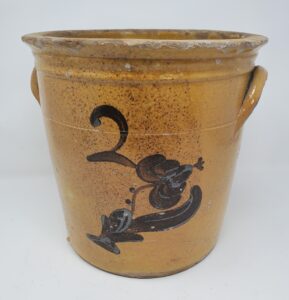 Whitewater two-gallon crock with a tooled rim, ear handle and incised line and clear lead glaze with a manganese flower under a painted "2". These is an interesting spray of manganese dots on the front. Private collection.. 