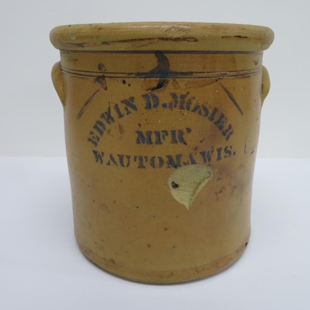 Wheel turned earthenware butter pot with lead glaze, oversized round rim, ear handles, and incised lines at the handles. It has a hand painted capacity and stenciled name "EDWIN D. MOSIER / MFR / WAUTOMA WIS". 	
10 1/2"H x 10" diam. Photo is from the Decorative Arts Database item 508-1. PC088