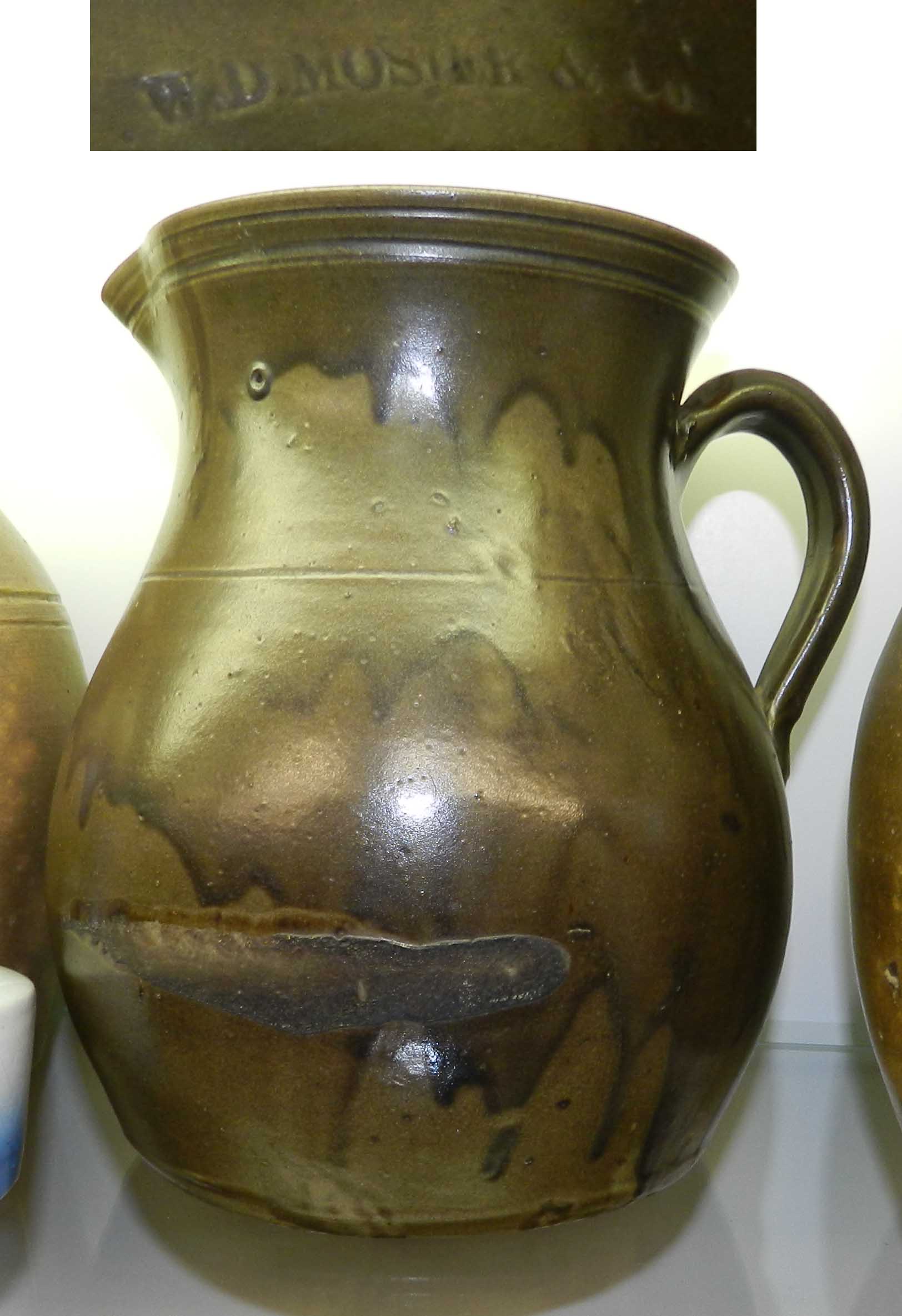 Earthenware pitcher with drippy olive green lead glaze, handle and incised lines around the rim and one ast the shoulder. It is stamped "W.D. MOSIER &CO." below the pouring spout. Private collection.