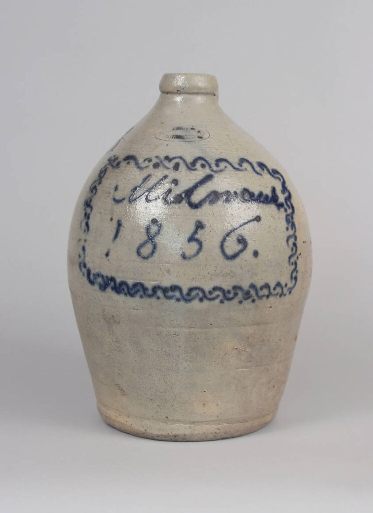 One of a handful of pieces of dated Wisconsin stoneware, this jug may have been made to commemorate the founding of the pottery in 1856. It is slip trail decorated with an elaborate square border around "Milwaukee" in script over "1856." with the Hermann oval stamp.